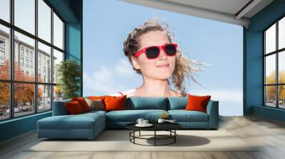 Young woman hipster millennial on beach during sunny day with red sunglasses in Miami, Florida with blue sky background, smiling happy Wall mural