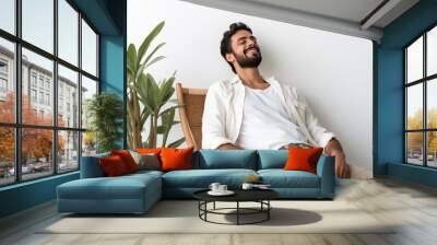 Calm young Arab man relaxing in armchair against white studio wall, copy space  Wall mural