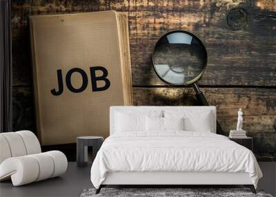 Job search and job hunting concept. A word JOB in a notebook next to a magnifying glass on old boards  Wall mural