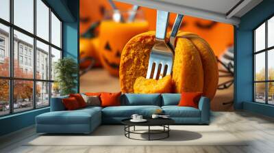 orange pumpkin cake in Halloween style on the table. on the side a fork and knife and an orange drink in a transparent glass. Halloween atmosphere Wall mural