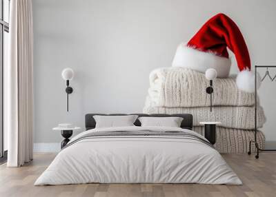 Pile of colorful sweaters with a Santa hat placed on top, creating a festive and cozy winter display. Wall mural