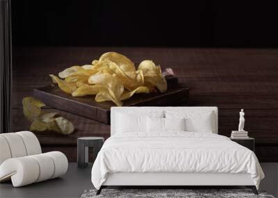 Potato chips on a wooden board and a dark wooden table Wall mural