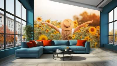 Beautiful curly young woman in a sunflower field holding a wicker hat. Portrait of a young woman in the sun. Summer. Wall mural