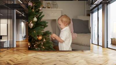 little cute girl of 2 years in pajamas decorates a christmas tree. christmas. new year. holidays. co Wall mural