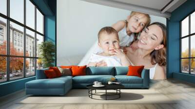 Young beautiful mother Holds her little daughters in her arms. Home comfort. Mothers Day. Wall mural