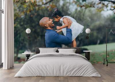 beautiful indian father playfully hugging his child daughter girl in the park with trees and greenery Wall mural