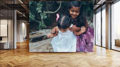 beautiful indian sisters girls hugging in the park with trees and greenery Wall mural