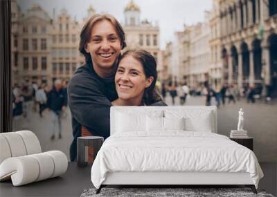 couple standing and hugging in front of a crowded city center in europe grand palace Wall mural