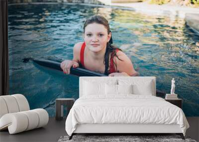 teenage girl with freckles and wet hair in red bathing suit in a pool during the summer Wall mural