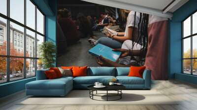 Young adults sitting at a Bible study in church looking at their bibles cropped with copy space Wall mural