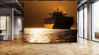 As the sun sets, the cargo ship appears as a dark silhouette against the horizon, the containers outlined in golden light Wall mural