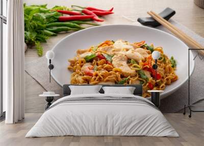 Spicy stir fried instant noodle with sliced chicken breast and thai basil leaves in white plate Wall mural