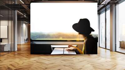 A beautiful hipster asian woman traveling on the train looking to the view through the window. Wall mural