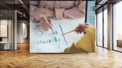 Data-Driven Decisions: A close-up of a business meeting, two hands point to graphs and charts, symbolizing the collaborative process of analyzing data and making informed decisions.   Wall mural