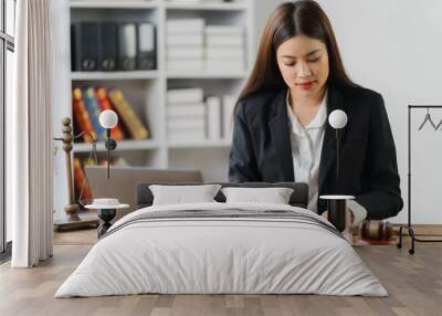 Focused Legal Professional: A young Asian female lawyer meticulously reviews documents at her desk, showcasing professionalism and dedication in a modern law office setting.  Wall mural