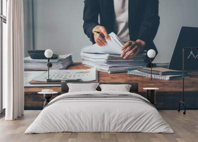 Overwhelmed by Paperwork: A businesswoman grapples with a towering stack of documents, her desk cluttered with the tools of a demanding profession, evoking the stress of deadlines and administrative o Wall mural