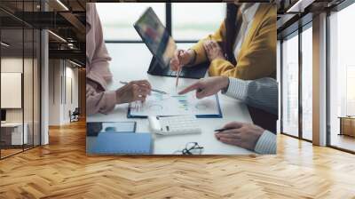 Strategic Collaboration: A close-up shot of a diverse business team collaborating on a project, pointing to a financial document and analyzing data on a tablet. Wall mural