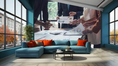 Strategic Collaboration: A diverse business team collaborates over financial data and charts in a modern office setting, reflecting the focused energy and shared ambition of a high-performing team.  Wall mural