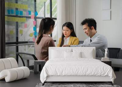 Team Brainstorming: Focused on a shared goal, three colleagues collaborate around a table, their faces illuminated by the natural light streaming in from a large window. Post-it notes adorn the glass. Wall mural