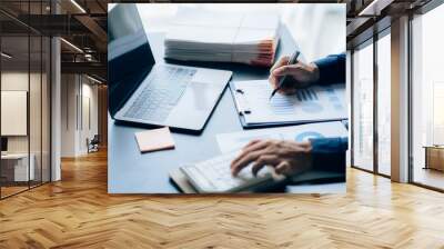 The hands of a male businessman are analyzing and calculating the annual income and expenses in a financial graph that shows results To summarize balances overall in office Wall mural