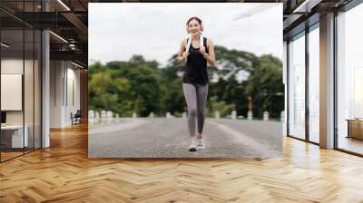 Young sports girl during a jog in the Park. Running, healthy lifestyle. Wall mural