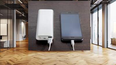 Smartphone charging with power bank on wood board Wall mural