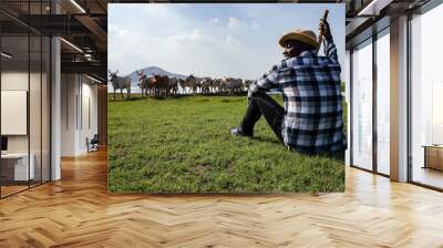 Africa American man feed and care the subsistence of cows in local farm near river and using a wood for control livestock. A farmer is a profession that requires patience and diligence Wall mural