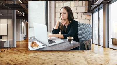 Young attractive woman sitting in a cafe in the morning before her work and planning tasks for the whole day. Beautiful lady talking on the phone and discussing business strategies with her colleague. Wall mural