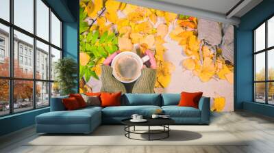 A cup of coffee in the hands of the girl on the background of yellow leaves. Wall mural