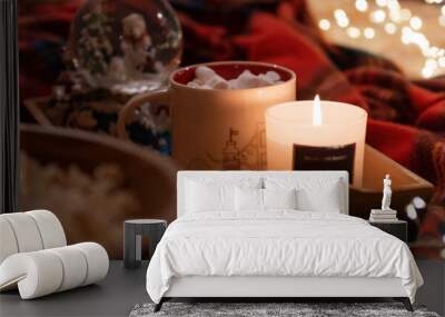 cup of hot chocolate and marshmallows and burning candle on tray in bed and garland glowing lights bokeh at home. taking care of yourself and relaxing on new year and christmas eve dark night. banner Wall mural