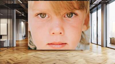 portrait face of candid happy little kid boy of five years old with problem allergic skin and long blond hair and green eyes on background of green plants during a summer vacation travel. banner Wall mural