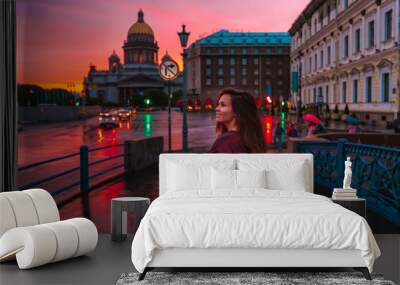 A young woman walks during a pink sunset in the center of St. Petersburg with a view of St. Isaac's Cathedr Wall mural