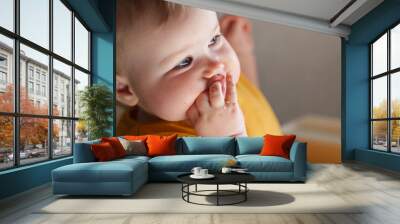 Baby toddler sits on a high chair and eats vegetables, the first lure Wall mural