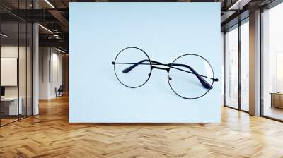 Round eyeglasses for vision on a blue background with space for text Wall mural