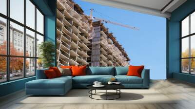 tower crane at a building site during the construction of blocks of flats. Detail of residential building under construction. Concrete structure with metal struts and temporary wooden railings.. Wall mural