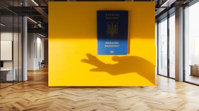 Blue Ukraine biometric passport on the energizing yellow background with silhouette of a woman hand. Immigration. Wall mural