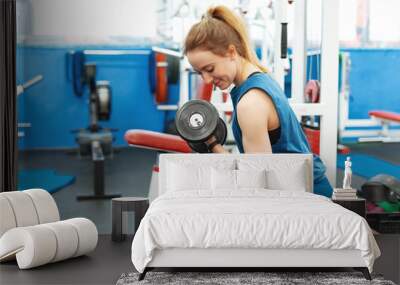 Fitness girl lifting dumbbell in gym Wall mural