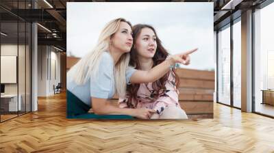 Two women sitting on stairs outdoor and pointing finger Wall mural