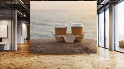 two brown cup of drink on stone by the sunset sea Wall mural