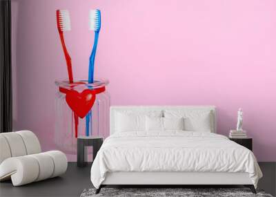 Love, relationship between man and woman, husband and wife, live together concept. A couple in love of two toothbrushes in a glass with a red heart. Valentine's Day card, pink background, copyspace Wall mural