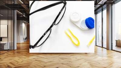 Top view of contact lenses, tweezers and an applicator for taking a lens from a case, glasses on a white. Optometry, vision correction, eye health, optics shop and ophthalmology clinic background Wall mural