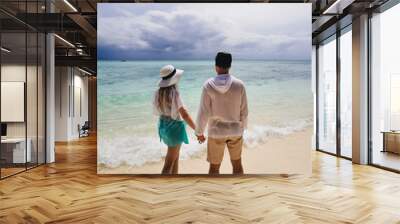 Young attractive man and woman in love walk and hug against the background of white sand and azure sea. Travel, Thailand, honeymoon Wall mural