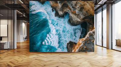 Aerial view of a rugged coastline with dramatic rock formations and crashing waves, showcasing the power of the ocean Wall mural