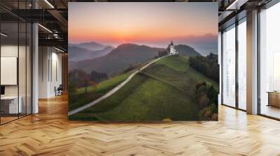 Aerial drone view of small beautiful church on top of a mountain in Slovenia at sunset. Beautiful autumn morning landscape Wall mural