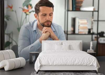 Concentrated caucasian businessman looking at laptop screen, watching online business webinar while sitting at the table in the office, analyzing and thinking Wall mural