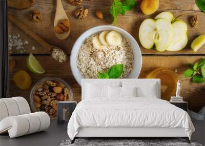 Dry raw oatmeal with ingredients for cooking healthy breakfast on wooden table top view Wall mural