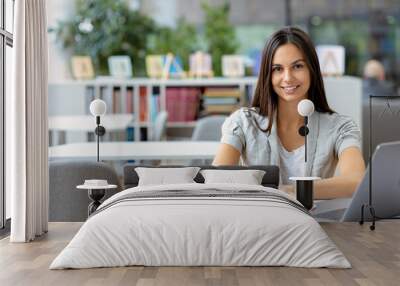 Learning, online education. Portrait of female freelancer or employee sitting at workplace, coworking. Smiling caucasian woman using laptop computer, working at modern office, smiles friendly Wall mural