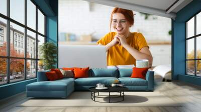 Online learning, portrait of red-haired happy caucasian female freelancer or smiling woman student using a laptop for a video call with a teacher, distance education concept Wall mural