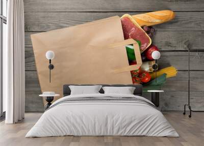 Paper bag full of different food on wooden background Wall mural