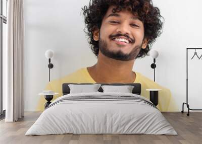 Portrait of Asian man with curly hair and happy smile. Young Indian male student smiling joyfully standing on a white background Wall mural